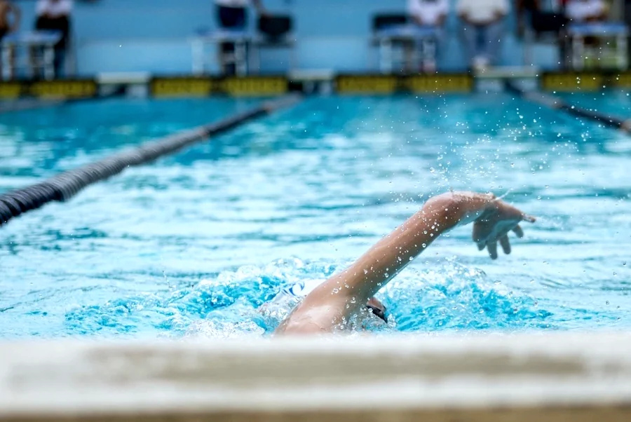 A swimmer mid-stroke next to a lane rope